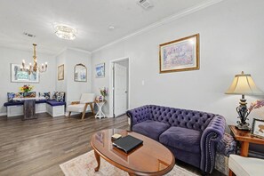 A living room with a purple sofa, a wooden coffee table, and a white door. - Cottage by The Sea, Family Retreat w/ Game Room (Biloxi)
