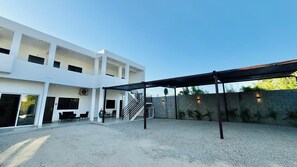 Un edificio moderno con un espacio exterior cubierto, una escalera y suelo de grava.