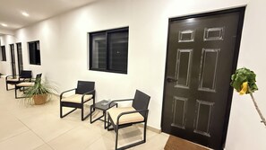Zona de recepción con una puerta negra, una planta en maceta y asientos.