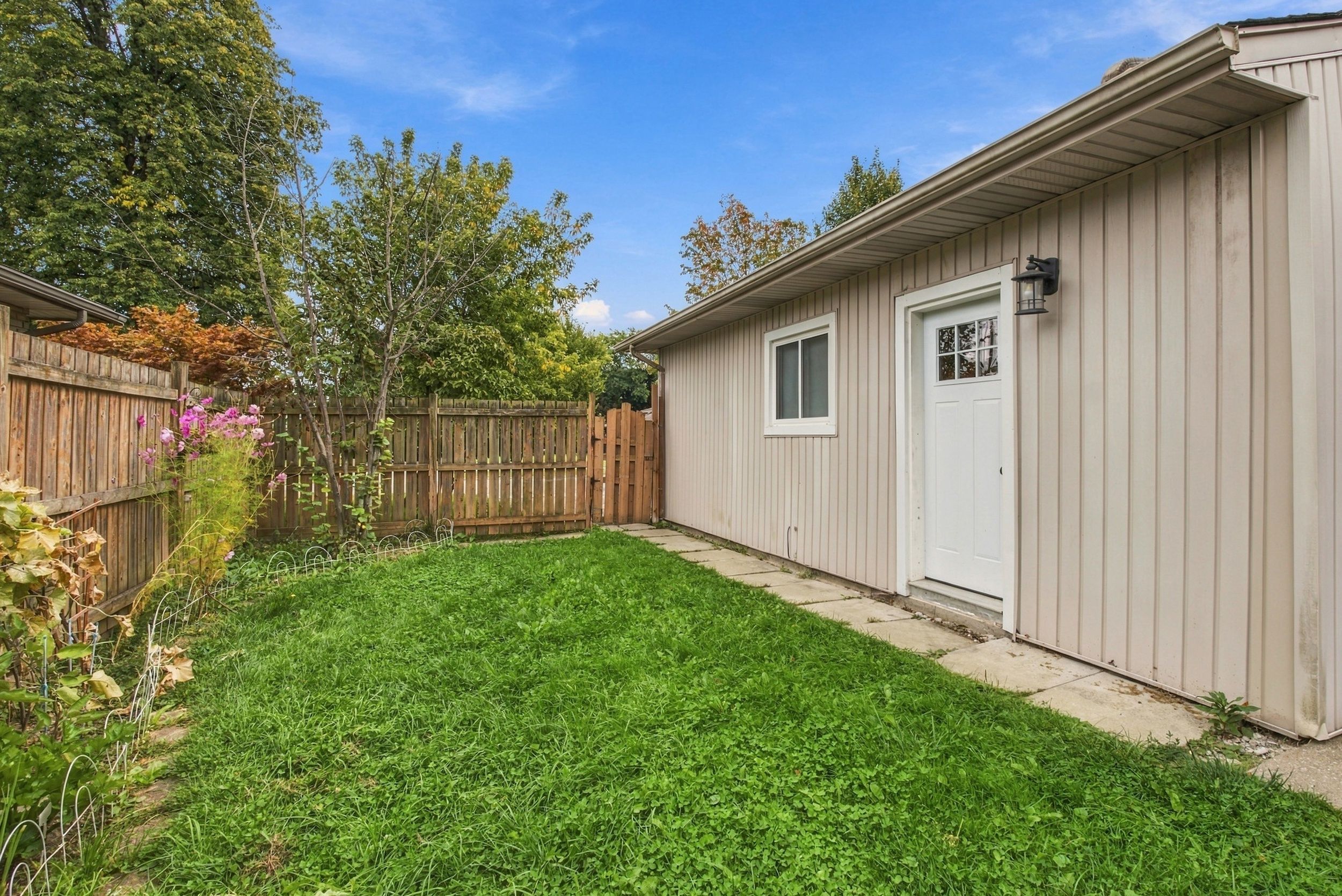 A residential backyard with a wooden fence, a shed, and a lawn.