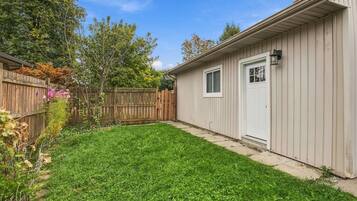 A residential backyard with a wooden fence, a shed, and a lawn.