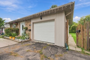 A residential garage with a white door, a brick house, and a wooden fence. - The Chic Studio in Niagara College (Welland)