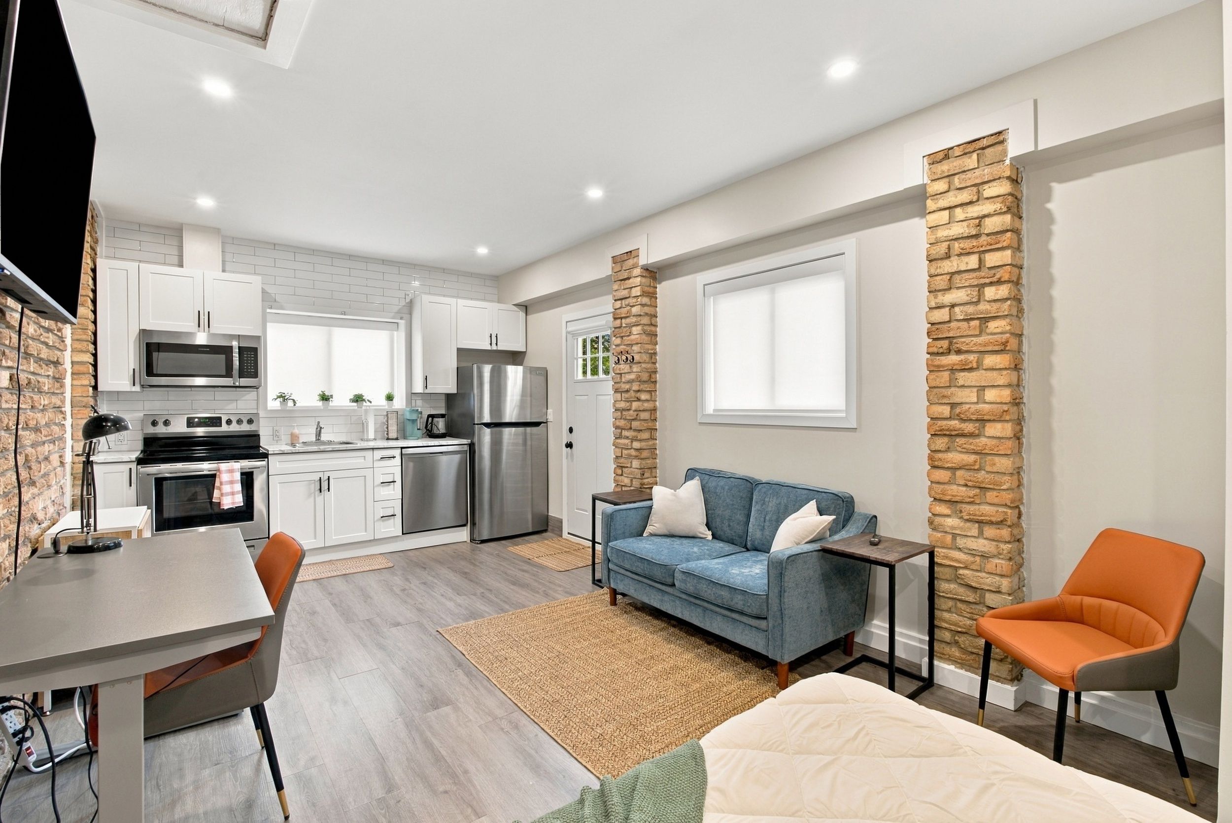 Un espacio habitable pequeño con kitchenette, un sofá, una mesa de centro y un televisor.