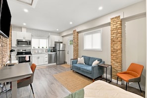 A compact living space with a kitchenette, a sofa, a coffee table, and a TV. - The Chic Studio in Niagara College (Welland)