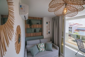 Un salon moderne avec un canapé gris, des œuvres d’art décoratives au mur et un luminaire suspendu au plafond en osier.