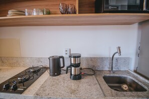 Une cuisine équipée d’une cuisinière à gaz, d’une machine à café, d’une bouilloire et d’un évier.