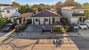 A residential house with a gated driveway, a fire hydrant, and parked cars. - Sunset Villa | Pool ·BBQ ·Outdoor kitchen & Grill (Hialeah)