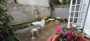 Un patio con una mesa, sillas, una planta en maceta y un muro de ladrillo.