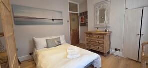 Un dormitorio con cama, cómoda, espejo y un cuadro en la pared.