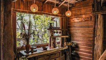 Un intérieur rustique en bois, avec un comptoir en bois, des luminaires suspendus et une fenêtre donnant sur les arbres.