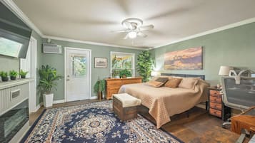 A bedroom with a bed, a desk, a chair, a radiator, a window, and a ceiling fan.