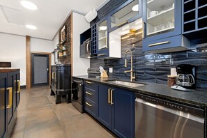Una cucina moderna con mobili blu scuro, elettrodomestici in acciaio inossidabile e un piano di lavoro nero.