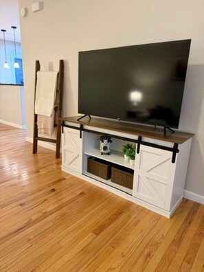 A wooden floor, a white entertainment unit with a TV, and a ladder.