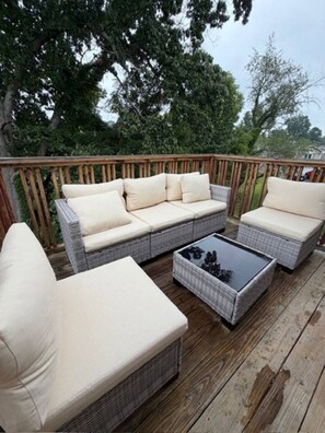 Eine Terrasse mit Korbmöbeln, darunter eine Couch und ein Couchtisch.