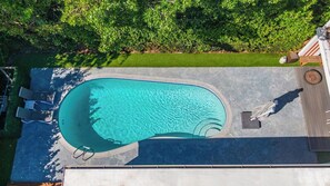 An aerial view of a swimming pool with a surrounding deck, a lounge chair, and a small table. - Casa Oasis | Fire Pit | Heated Pool | Pool Table (Miami)