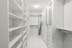 A narrow walk-through closet with white shelving units and drawers. - Casa Oasis | Fire Pit | Heated Pool | Pool Table (Miami)