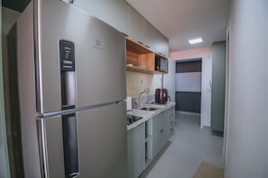 A compact kitchen with a built-in refrigerator, microwave, and a coffee maker on the counter. - Nixxus 316 (Ipojuca)