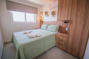 A bedroom with a bed, a nightstand, a wardrobe, and a window. - Nixxus 316 (Ipojuca)