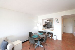 Un espacio habitable compacto con comedor, kitchenette y una puerta que da a otra habitación.