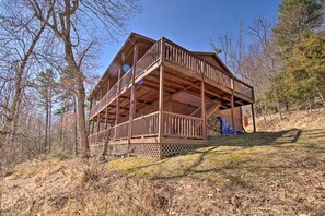A cabin with a wooden deck and multiple levels, surrounded by trees. - Woodsy WV Cabin near Lost River w Deck & Fire Pit! (Mathias)