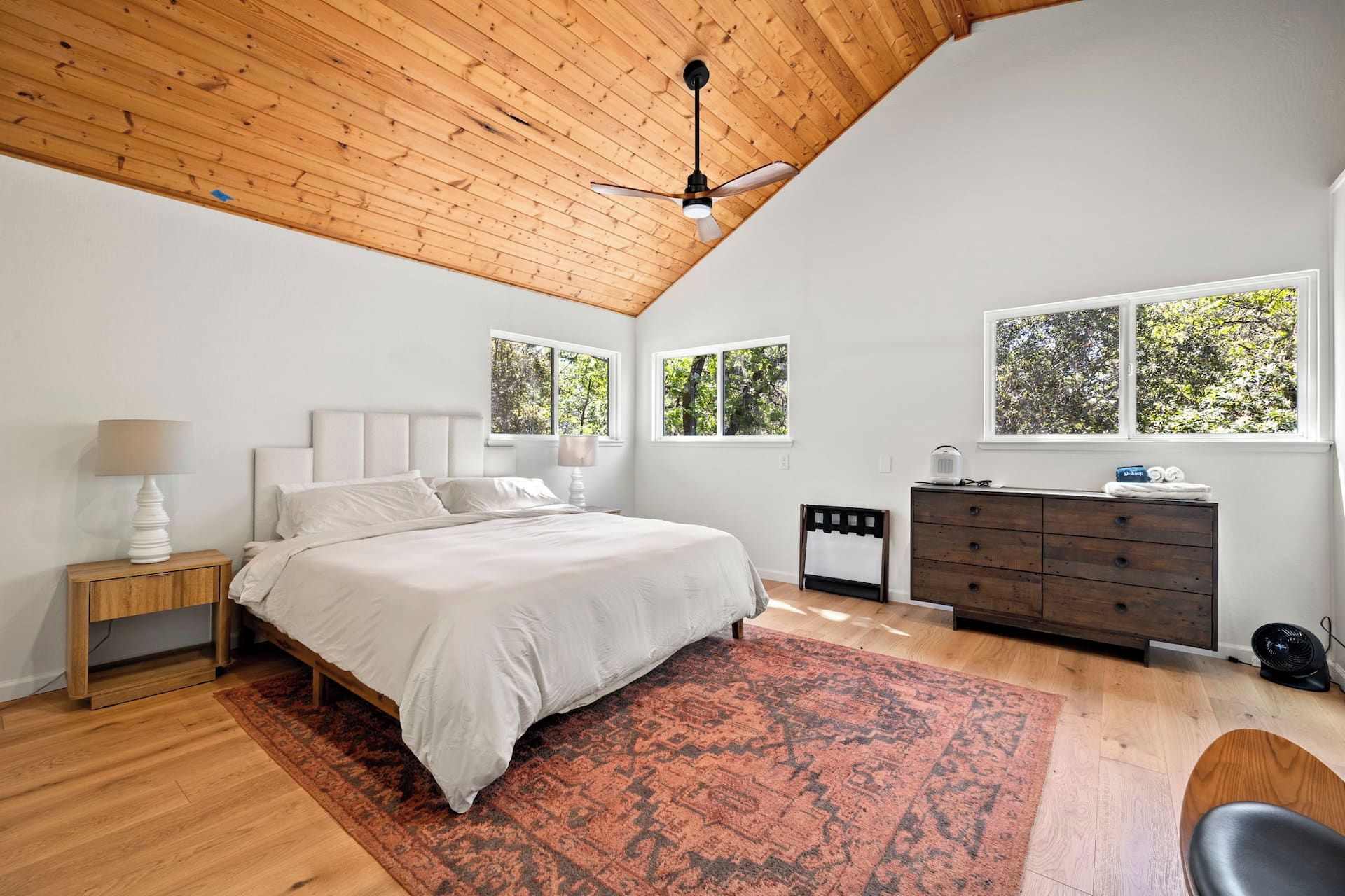 A bedroom with a bed, nightstands, a dresser, and a ceiling fan.
