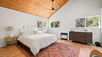 A bedroom with a bed, nightstands, a dresser, and a ceiling fan.