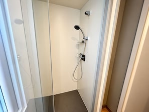 Una ducha moderna con cabezal de ducha de mano y grifo empotrado.