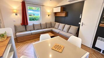 A modern living room with a sectional sofa, a dining table, and a kitchen area.