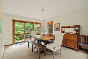 A dining area with a wooden table, white chairs, and a bench. There is a wooden cabinet with a mirror and a statue on top. - "Shanty Springs Retreat" -  Your Creekside Oasis (Banner Elk)