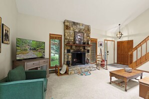 A living room with a stone fireplace, a television, a sofa, and a staircase. - "Shanty Springs Retreat" -  Your Creekside Oasis (Banner Elk)