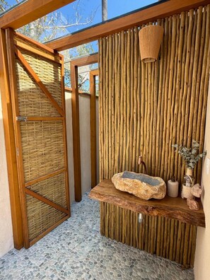 A spa area with a wooden bench, a stone basin, and a bamboo wall. - Amore'mare | Charm, Comfort and Sea (Ubatuba)