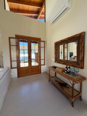 A spacious room with a wooden ceiling, a large mirror, and a console table with decorative items. - Amore'mare | Charm, Comfort and Sea (Ubatuba)