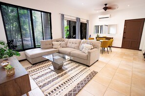 Uma sala de estar moderna com um sofá seccional, uma mesa de centro de vidro e um tapete estampado.