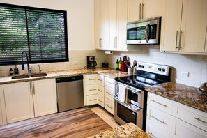Eine moderne Küche mit weißen Schränken, einem Backofen, einer Mikrowelle und einer Kaffeemaschine.