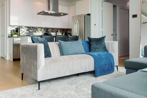 A modern living room with a sofa, a coffee table, and a kitchen in the background. - One-Of-A-Kind Parklawn Penthouse! Unreal Lake View | Parking Available (Toronto)