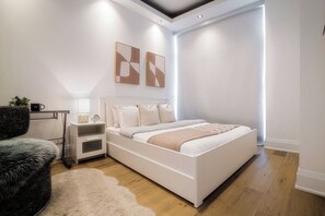 A modern bedroom with a large bed, bedside tables, a nightstand, a chair, and abstract wall art. - One-Of-A-Kind Parklawn Penthouse! Unreal Lake View | Parking Available (Toronto)
