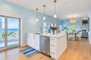 A modern kitchen with a large island, white cabinetry, and pendant lighting. - Luxury Gulf-Front Escape 4 Bedrooms, Private Pool & Stunning Views (Sanibel)