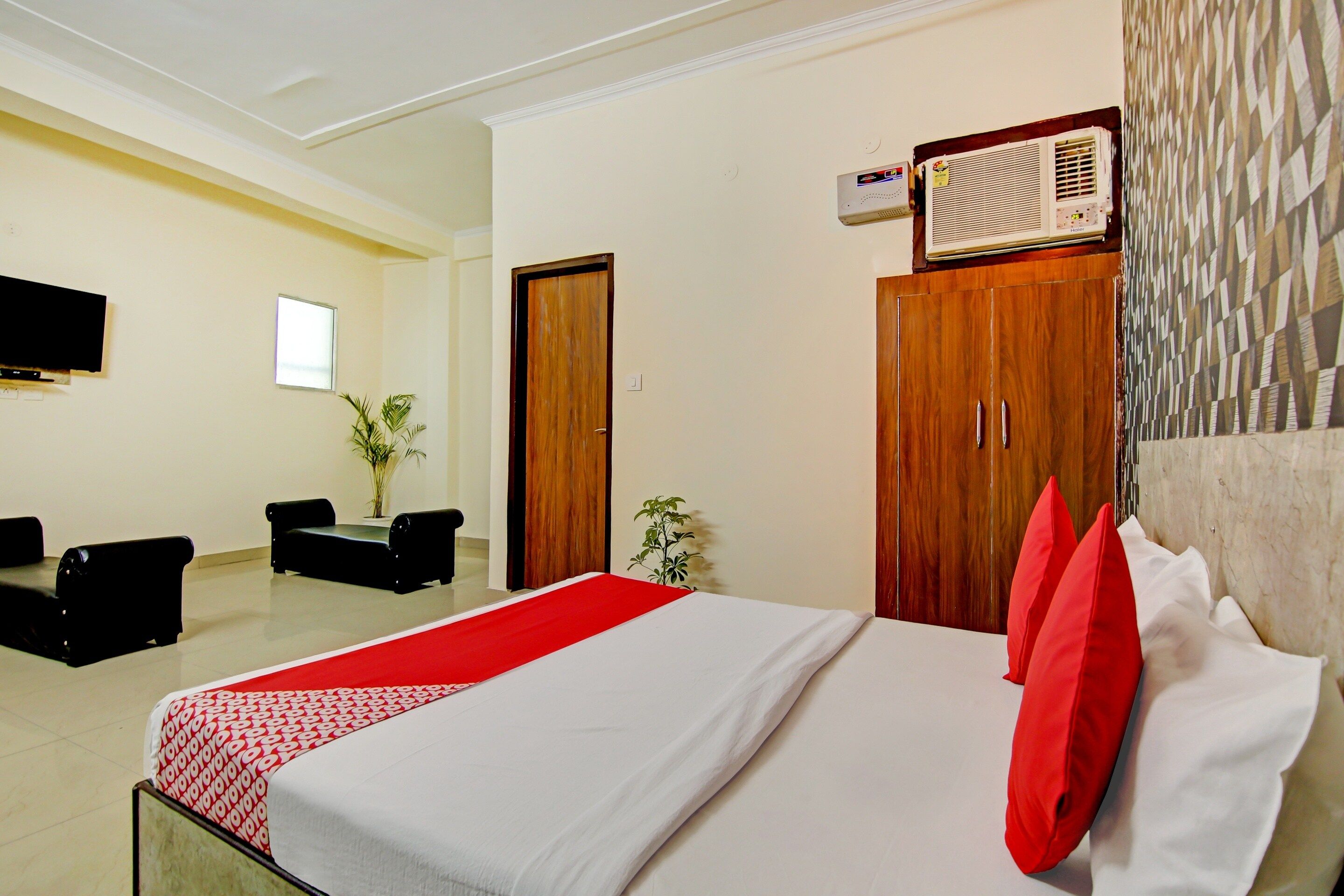 Habitación de hotel con cama, escritorio, silla, televisión y calentador instalado en la pared.