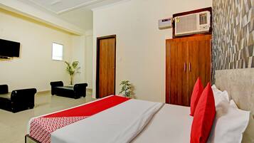 Habitación de hotel con cama, escritorio, silla, televisión y calentador instalado en la pared.