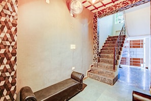 A room with a patterned wall, a bench, a staircase, and a fan. - Hotel O Sky In Near By Sector 62 (Ghaziabad)