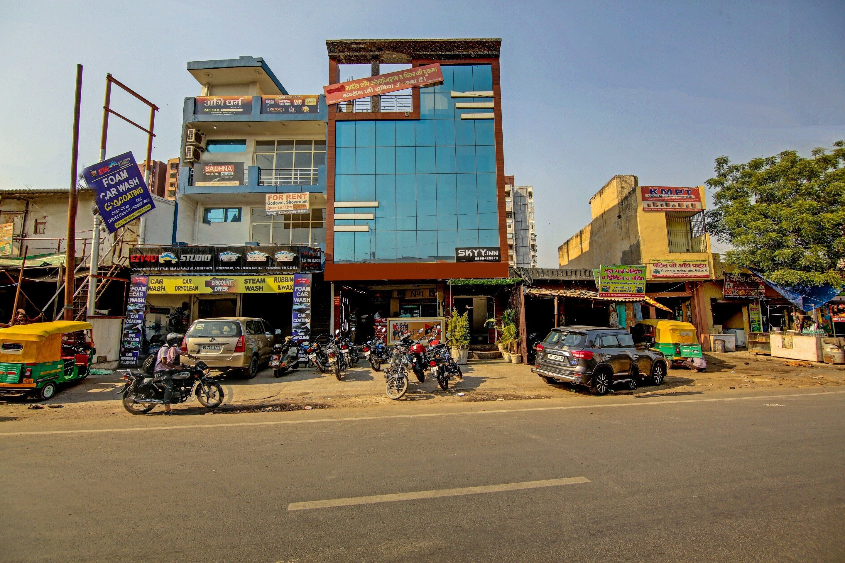 A multi-story building with various commercial establishments on the ground floor, including a car wash and a rental service.