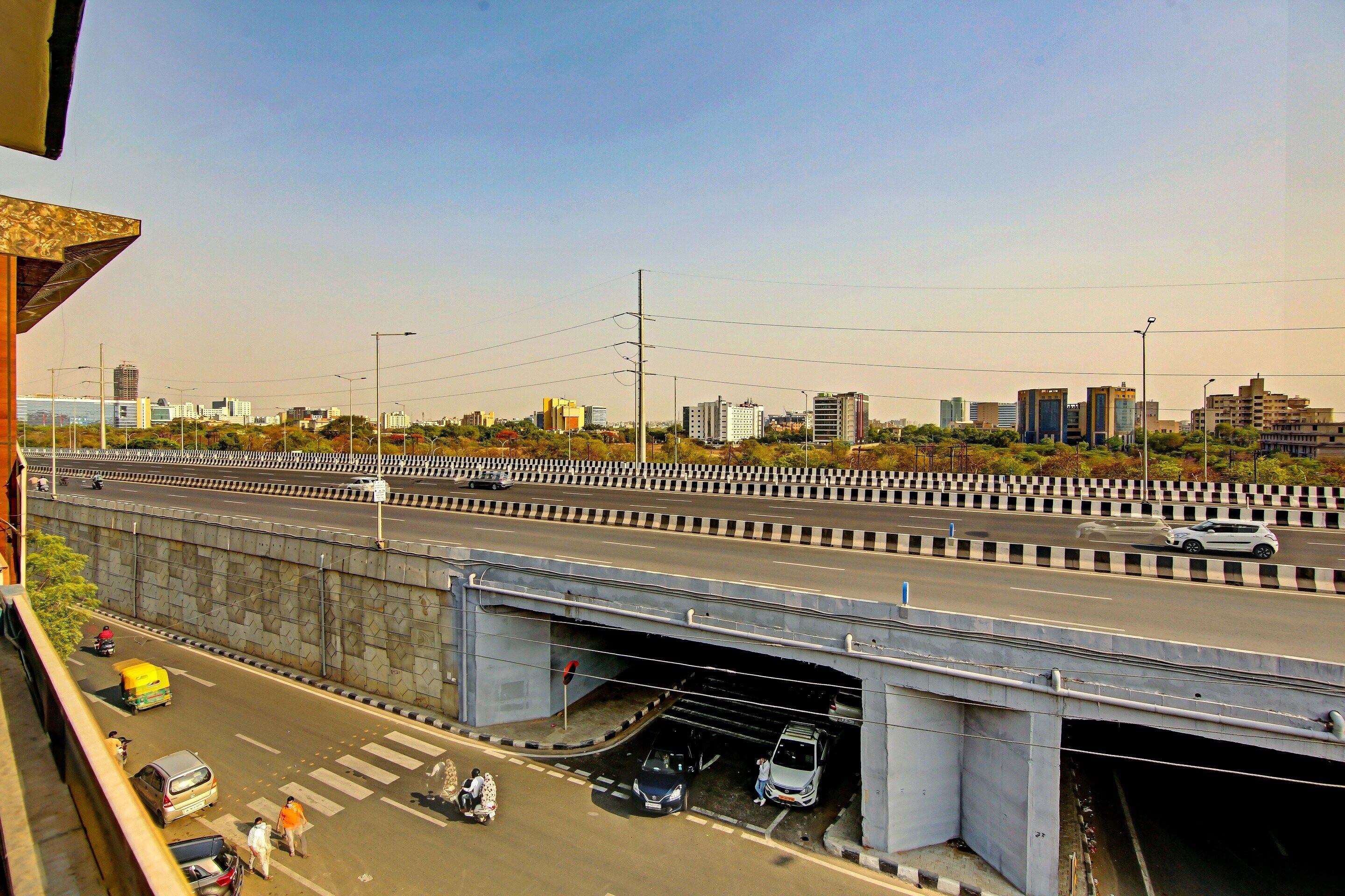 Eine mehrspurige Autobahn mit Fahrzeugen, einer Fußgängerbrücke und Stadtgebäuden im Hintergrund.