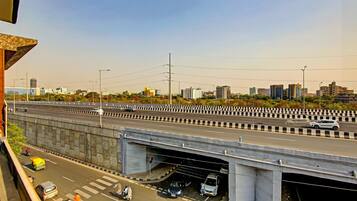 Eine mehrspurige Autobahn mit Fahrzeugen, einer Fußgängerbrücke und Stadtgebäuden im Hintergrund.