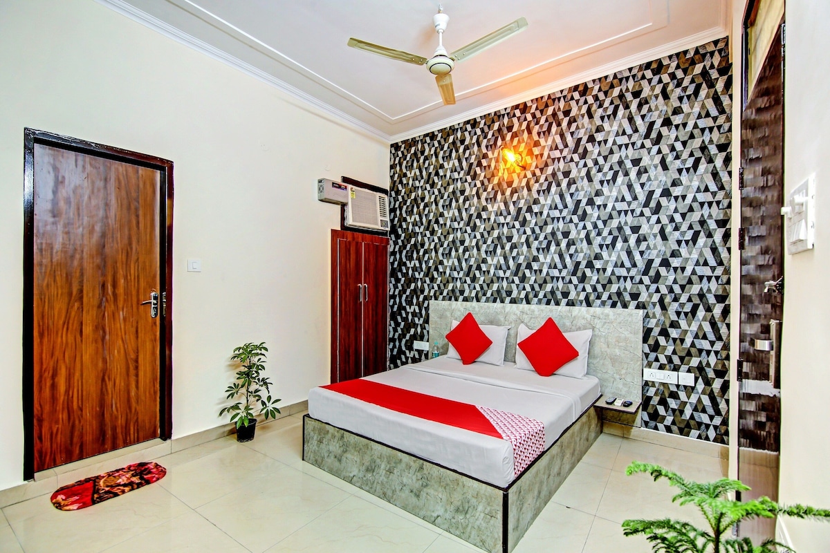 A bedroom with a bed, a ceiling fan, a wall-mounted air conditioner, and a patterned wall.