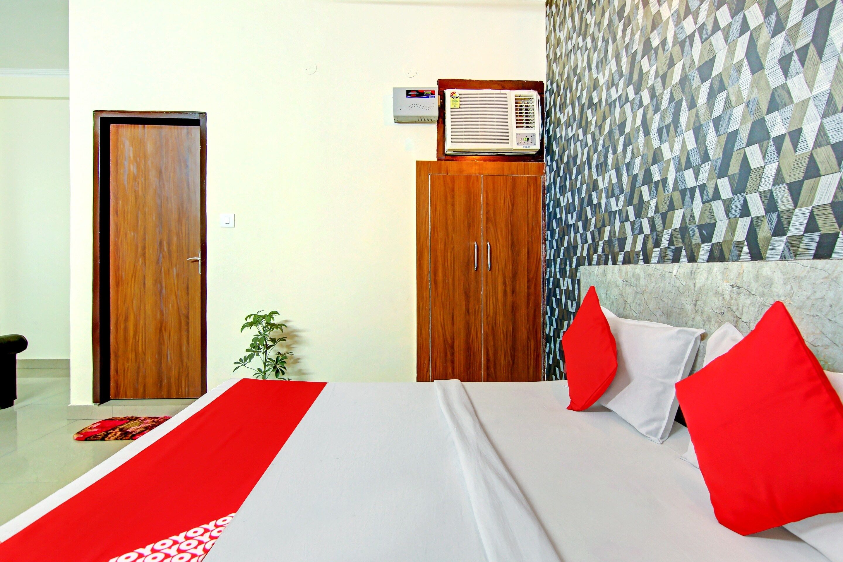 A hotel room with a bed, a wardrobe, a heater, and a patterned wall.