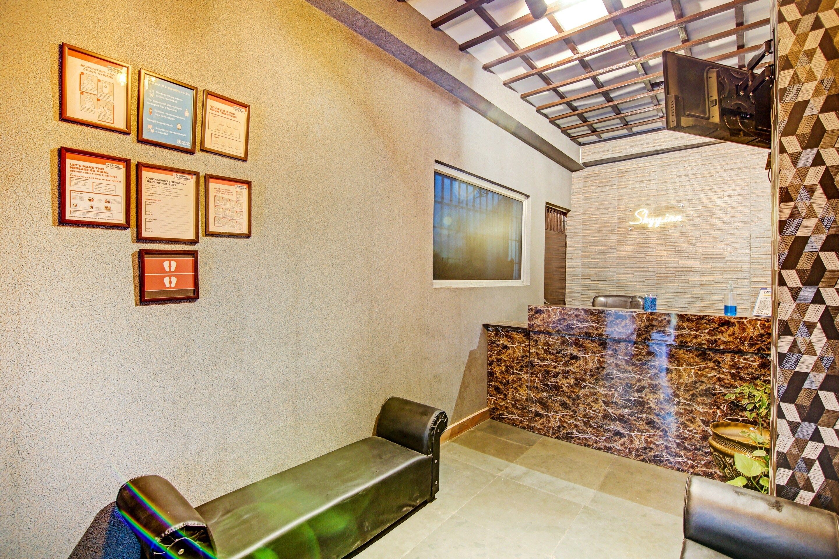 Un vestíbulo de hotel con carteles informativos enmarcados en la pared, un mostrador de recepción y un área de estar con bancos.