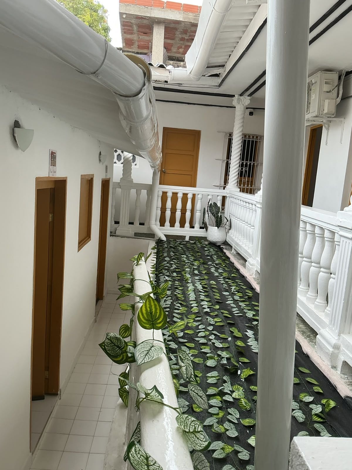 Un couloir doté d’un sol à motifs noirs et verts, de balustrades blanches et d’une colonne blanche.