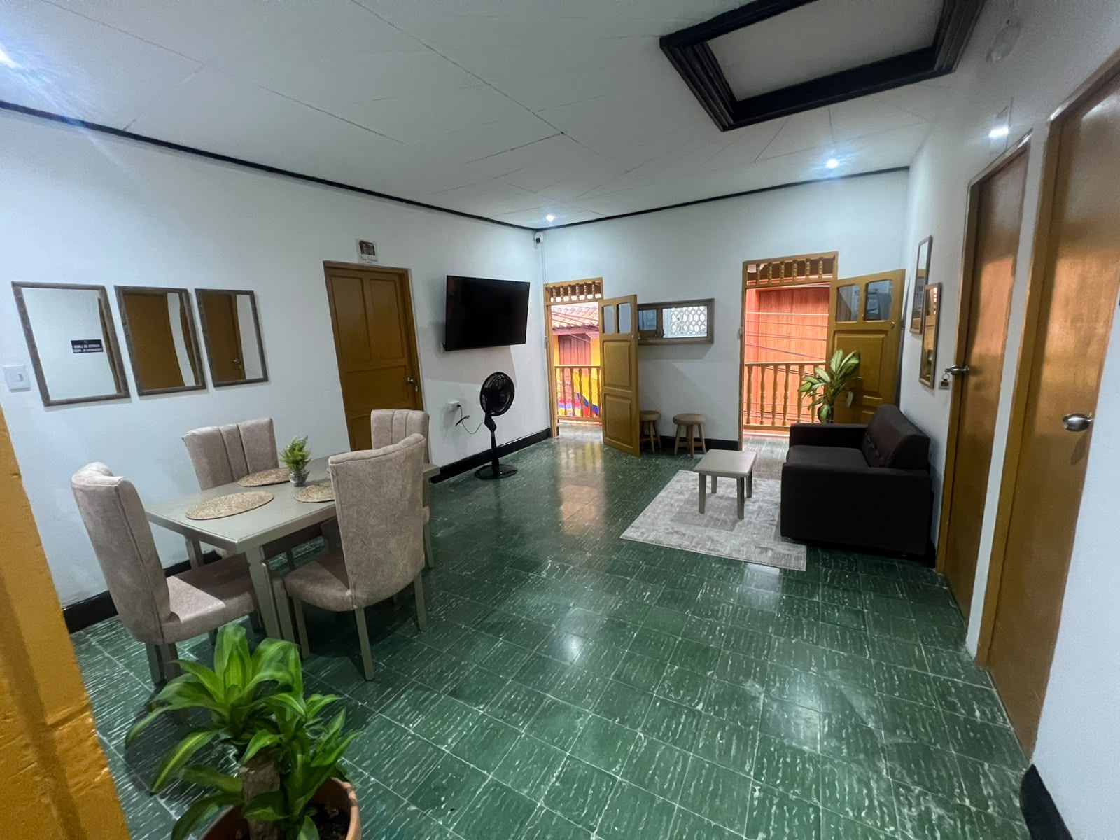 Un vestíbulo de hotel con zona de comedor, un sofá, un televisor y una puerta que da al exterior.