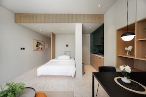 A modern bedroom with a bed, a desk, and a kitchenette. - Chic Studio in Upside Living | Burj Khalifa View (Dubai)