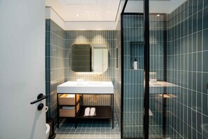 Un baño moderno con cabina de ducha de vidrio, un lavabo blanco y un espejo grande.